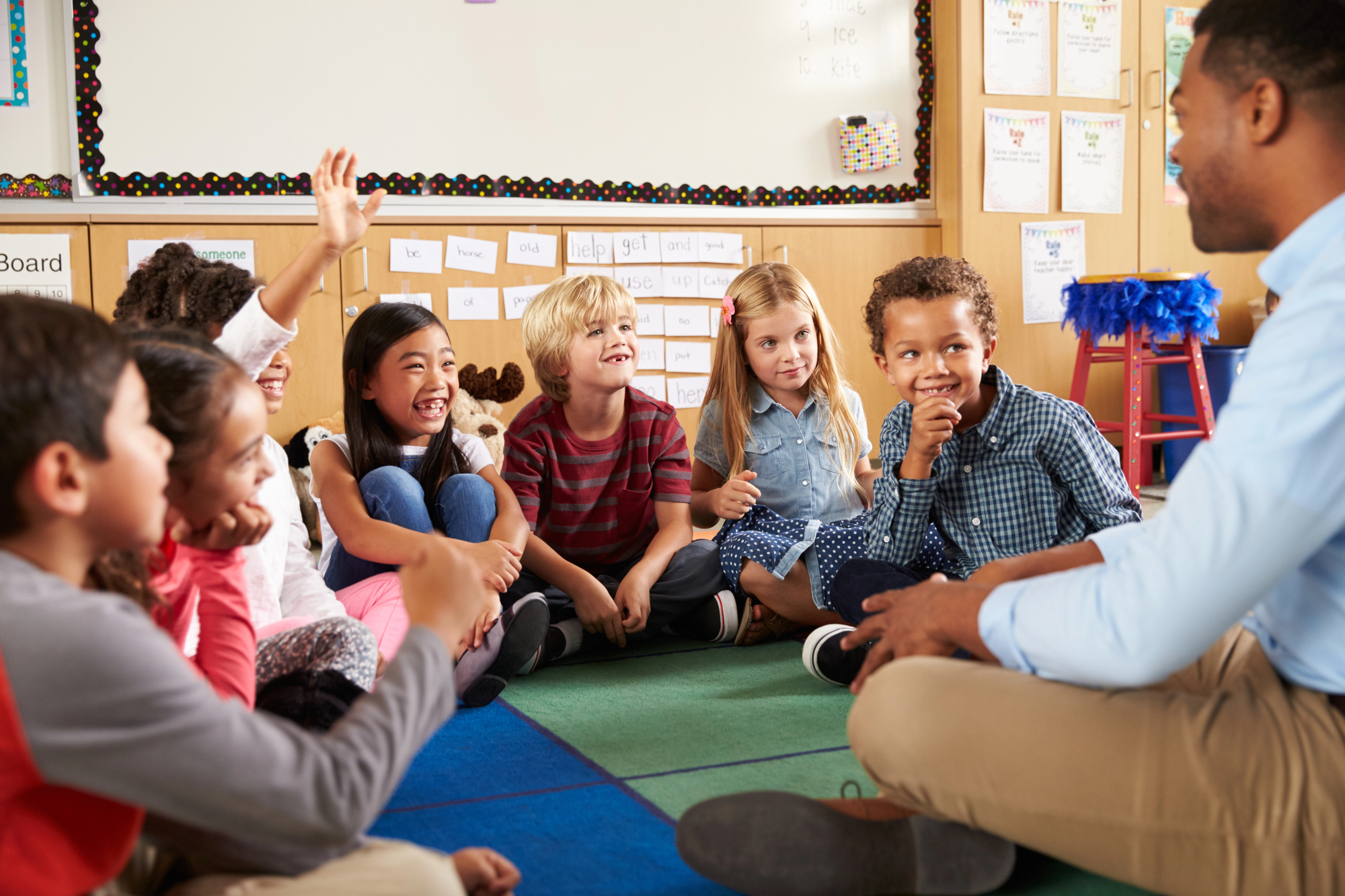 Lehrerin sitzt mit Kindern im Klassenzimmer am Tisch